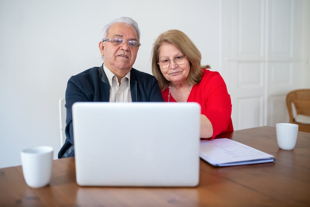 Elderly couple using a laptop at home, sharing a warm, intimate moment online.